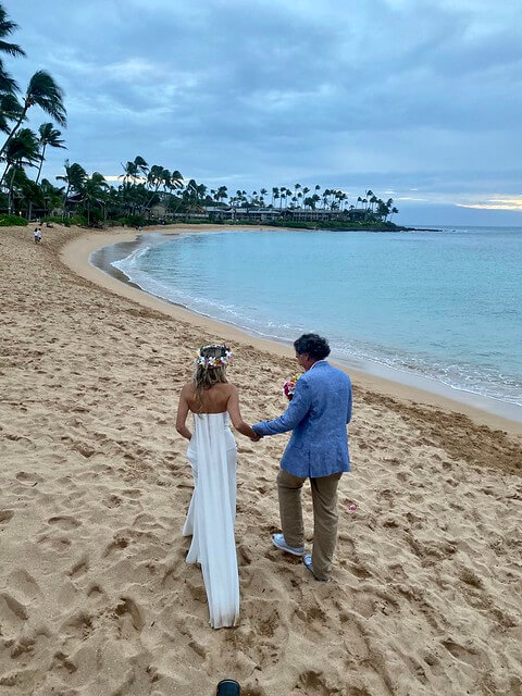 Bride and groom walk hand in hand on Napili Kai Beach, Maui, Hawaii.