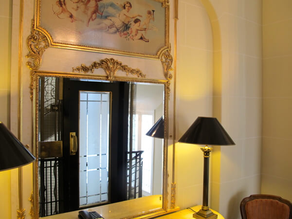 The vintage art deco lift is reflected in a hallway mirror at the Millennium Hotel Paris Opera