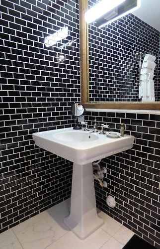 Retro pedestal sink and black tile in hotel room bathroom at The Langford Miami FL