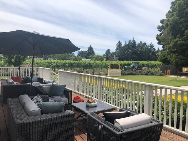 Wicker furniture and over-stuffed pillows await guests on the farmhouse back deck. 