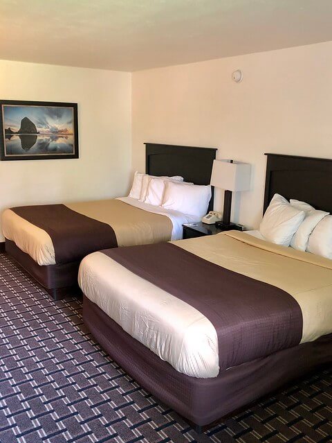 Two queen beds and a small table with desk lamp at Billings Hotel