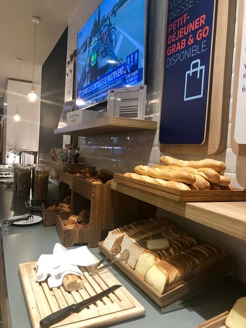 Fresh baguettes and sliced bread on the breakfast buffet table inside Holiday Inn Express Paris. 