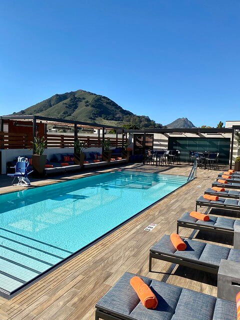 Hotel Cerro swimming pool with lounges, orange beach towels and mountain top in the background. 