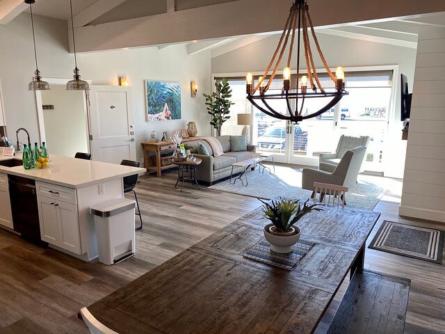 Dining room wooden table with nautical themed chandelier and open living room look out to Morro Rock. 