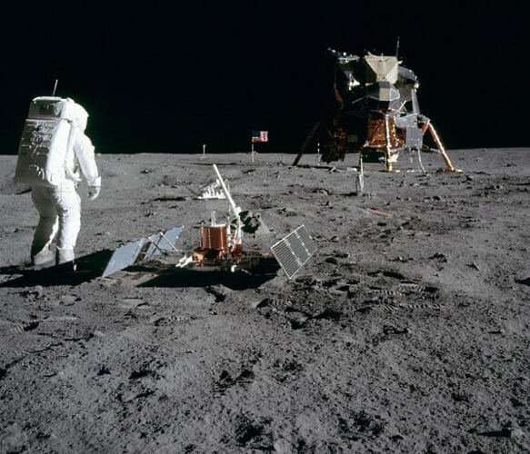 Astronaut Buzz Aldrin with scientific equipment, US flag, television camera and Apollo Lunar Module at Tranquility Base. Photo by Neil Armstrong