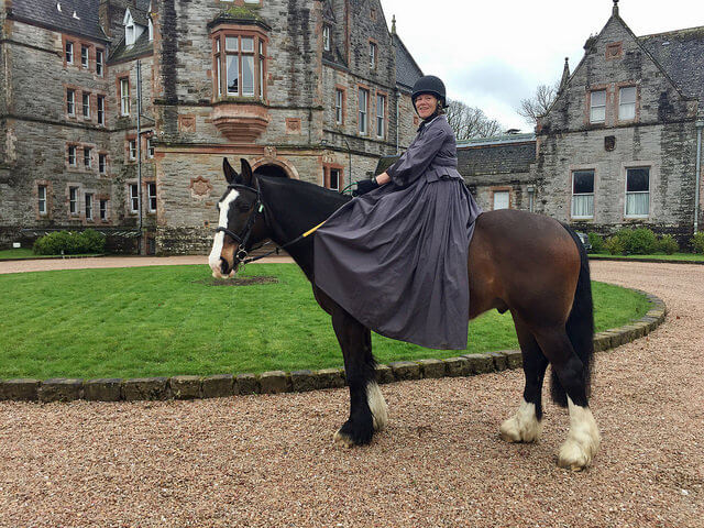 Equestrian travel expert Nancy D. Brown sits side saddle on a horse in front of Castle Leslie Estate in County Monaghan, Ireland.