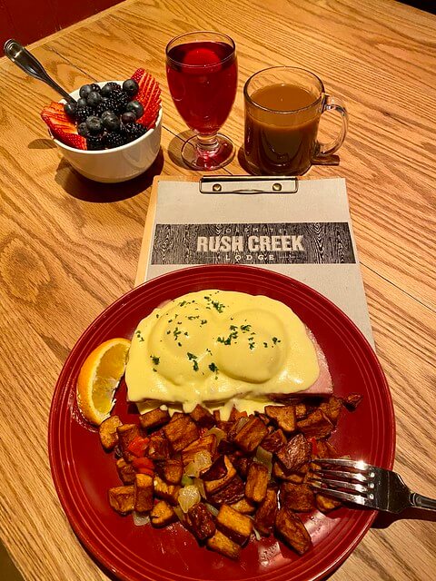 Rush Creek Lodge breakfast of Eggs Benedict, home fries, yogurt parfait with fresh berries, cranberry juice and coffee. 