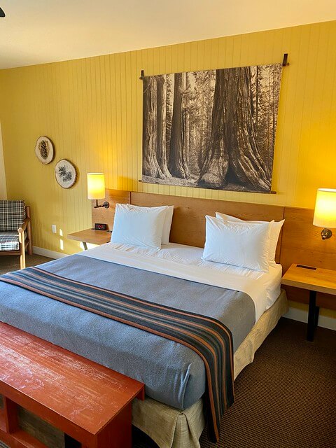 Rustic Rush Creek Lodge king room with custom art and feather pillows on the bed. 