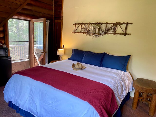 Eagle's Nest Cabin with king bed, white duvet, blue pillow cases in room with deck. 