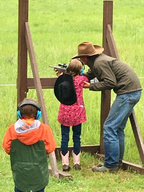 Wrangler assists young girl as she prepares to shot a 22 rifle at Bar W Guest Ranch in Whitefish, Montana