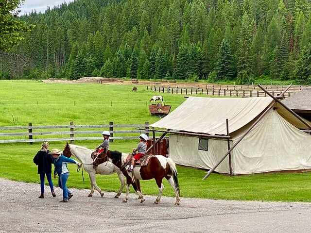 Twin brothers enjoy taking a horseback ride while being lead around Bar W Ranch by cowgirls in Whitefish, Montana.