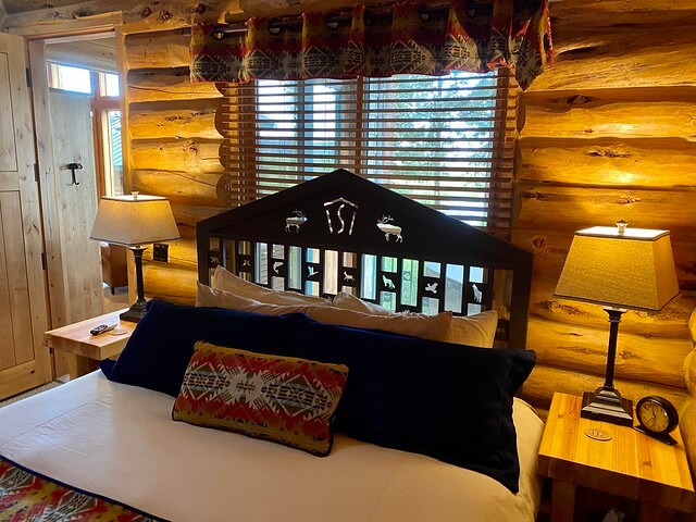 Luxury cabin with Penelton Woolen Mills bedding, custom Silvies Valley Ranch metal fabrication bed headboard inside log cabin king bedroom. 