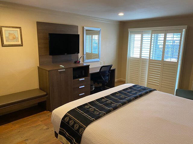 Pet-friendly hotel room features sliding glass door with wood shutters that opens to outdoor area. Great for people traveling with dogs.