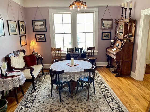 Heceta Lighthouse Bed and Breakfast west parlor with antiques, black and white photos and circular dining room table. 