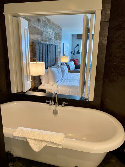 Cannery Pier Hotel clawfoot bathtub with open window to king bed