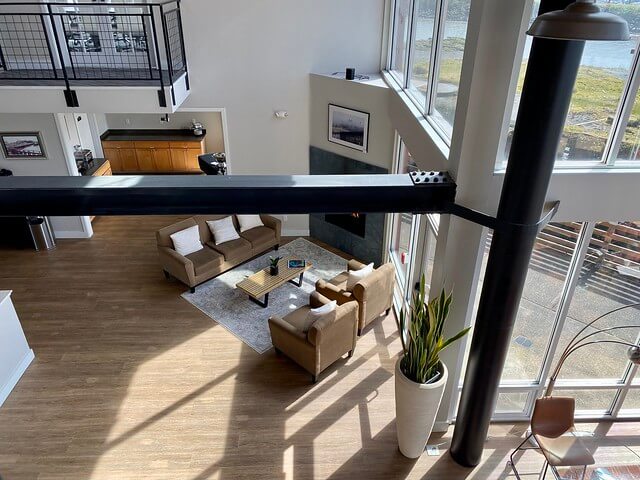 Cannery Pier Hotel lobby from the second floor. View of the exposed steel beam and sitting area with gas fireplace below. 