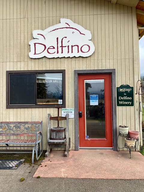 Delfino Vineyards tasting room with red door and Delfino dolphin logo over doorframe in Roseburg, Oregon 