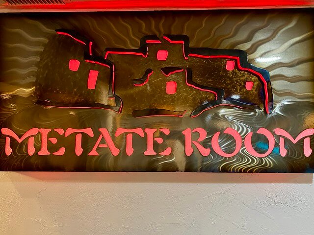 Metate Room restaurant sign with artwork depicting the restaurant. 