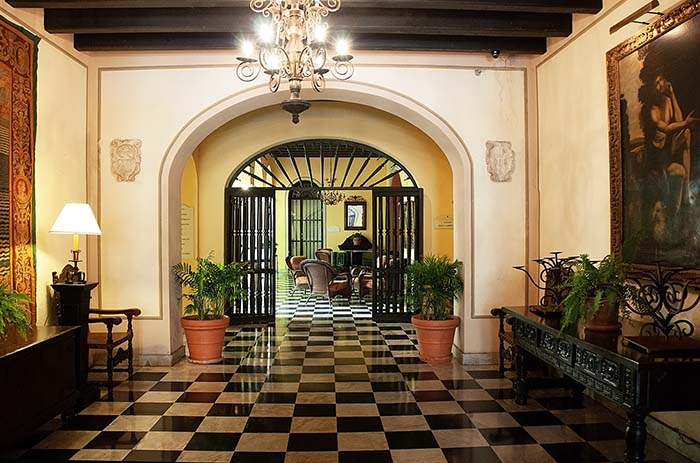 Lobby of Hotel El Convento with arched doorways, black and white checkered floors and ornate woodwork