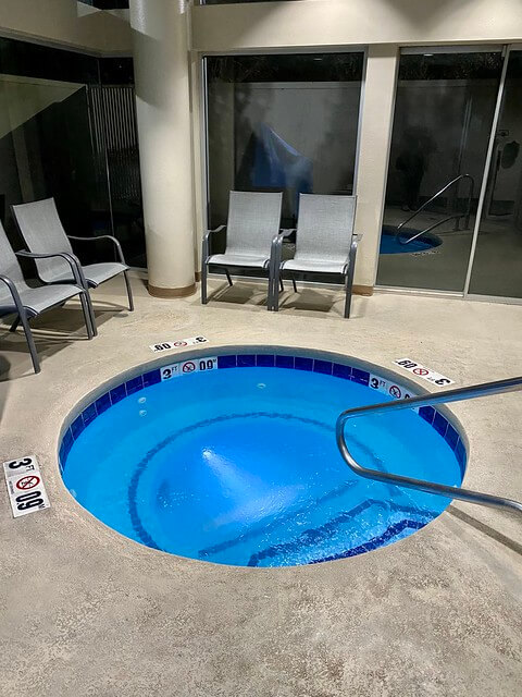 Holiday Inn Express Boise indoor, circular hot tub. Four metal chairs with white material surround the small hot tub. 