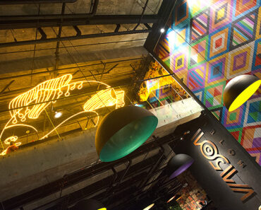 Detail of hotel lobby showing colorful beadwork wall and neon fish