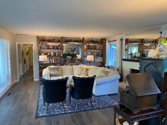 interior living room of the Stahlecker House, with a large seating area and floor-to-ceiling bookshelf 