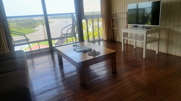 Aparment hotel room with coffee table and tv, with balcony overlooking Itaya River