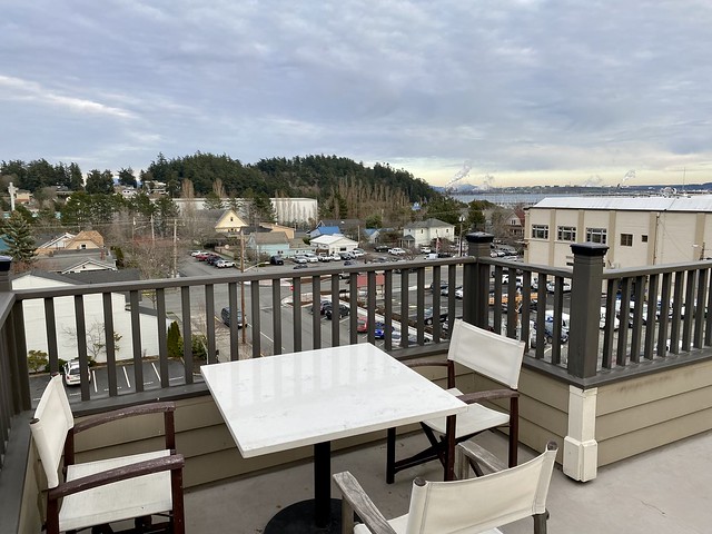 Majestic Inn rooftop patio with downtown Anacortes views. Square white table and 3 white canvas chairs flank the patio table. 