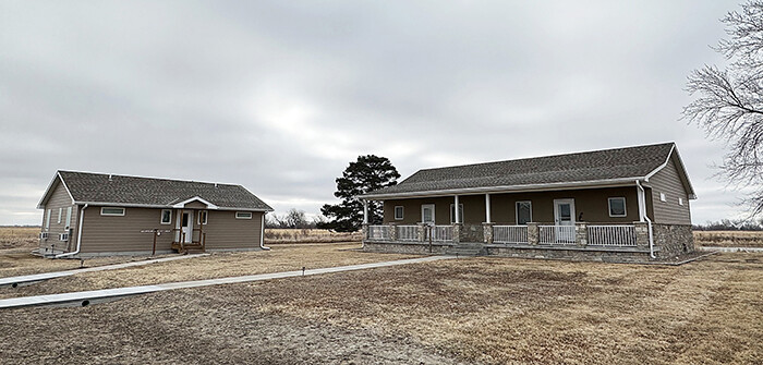 Two cottages, one smaller and one larger, in a field