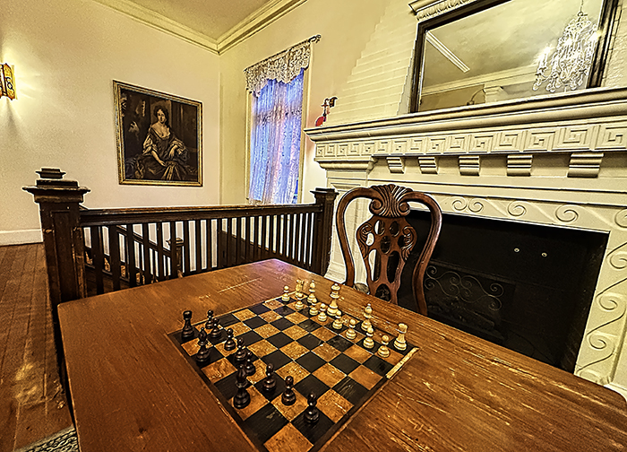 A chess board sits in front of a fireplace