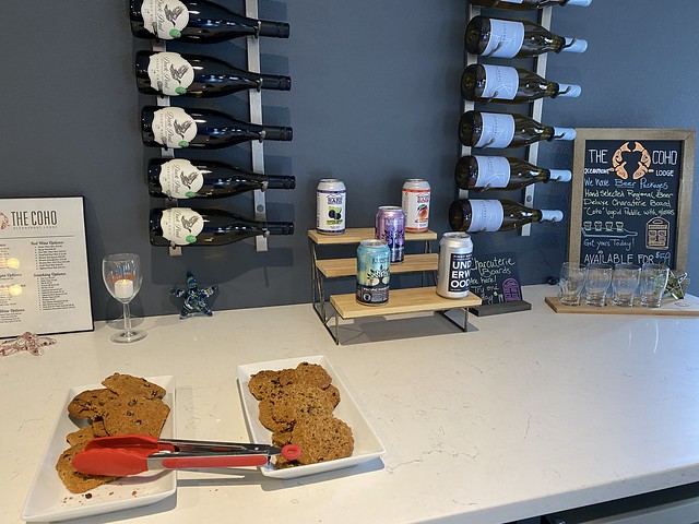 Wine bottles are hung on a rack, sideways, along with cans of beer displayed for sale at Coho Oceanfront Lodge in the hotel lobby. 