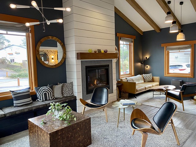 Coho Oceanfront Lodge lobby with gas fireplace. Beige leather sofa and navy sofa with cloth material and four throw pillows, flank the fireplace. Two modern chairs surround a wood coffee table. A green plant sits on top of square table. 