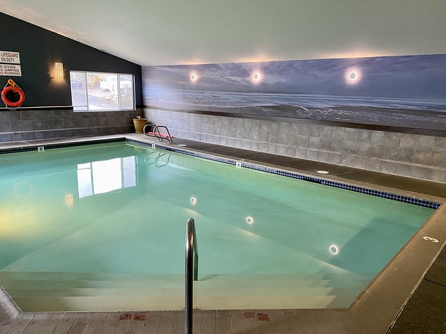 Indoor swimming pool with ladder and steps.