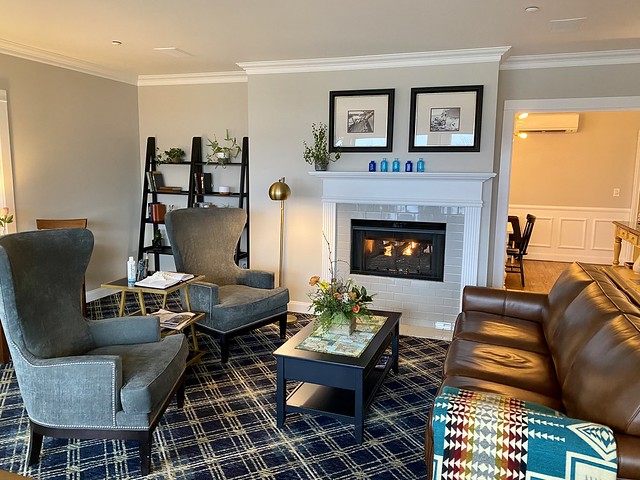 Saratoga Inn gas fireplace blazes. Brown leather sofa and 2 wing-back chairs flank the fireplace in the living room.