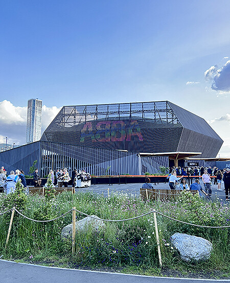 ABBA Voyage concert venue with blue sky and flowers at foreground