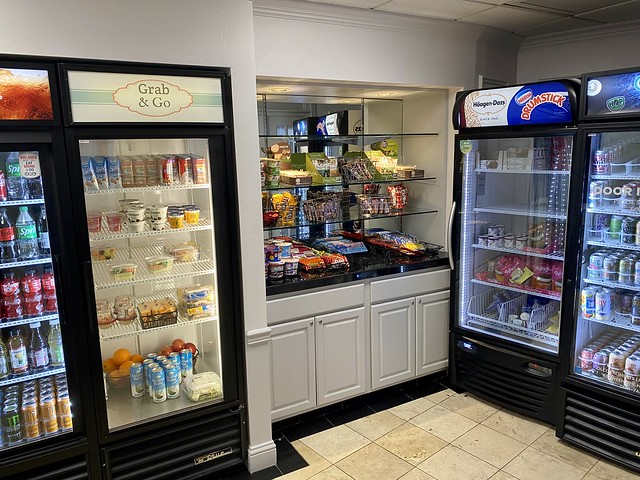 Grab & Go convenience shop with refrigerated and frozen food cases. Cases hold fruit, juices, ice cream and water. Snack bar with candy bars is between 2 refrigerated food cases.