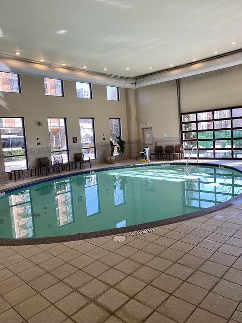 Indoor swimming pool at Crowne Plaza. Eight glass windows and a roll up glass, garage door, light up the pool room.