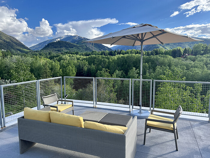 Outdoor patio furniture on a deck with mountains and blue sky