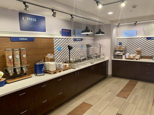 Holiday Inn Express breakfast buffet with silver chafing dishes, 3 cold cereal dispensers and a bagel and English Muffin holder. 