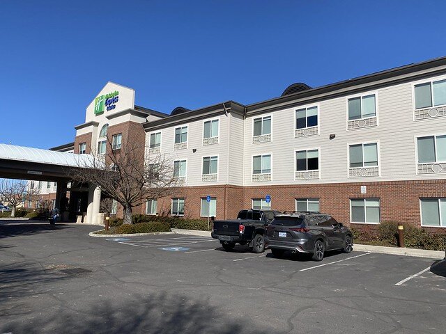 Holiday Inn Express front of the brick hotel with a car and truck parked in the parking lot. 