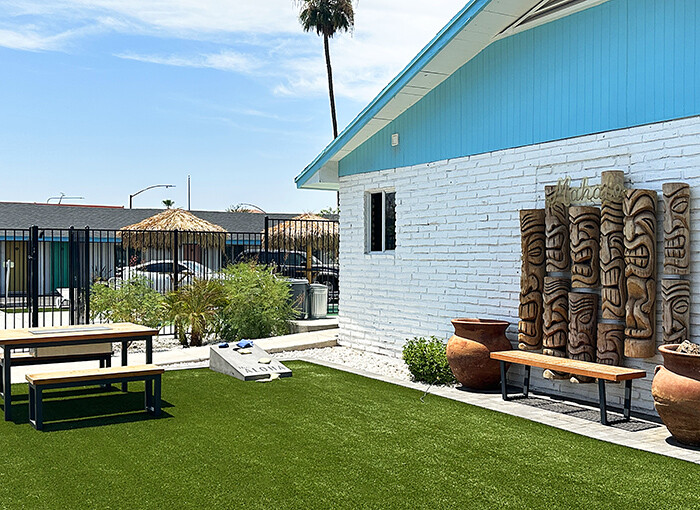 A turf lawn complete with picnic tables, cornhole and tiki decor.