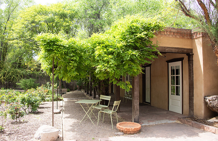 Vine covered historic adobe building that houses suites.