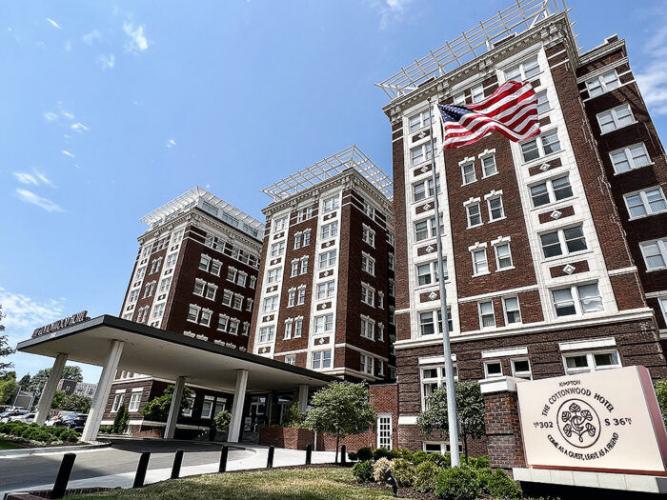 Large brick historic building with white windows and American flag in front.