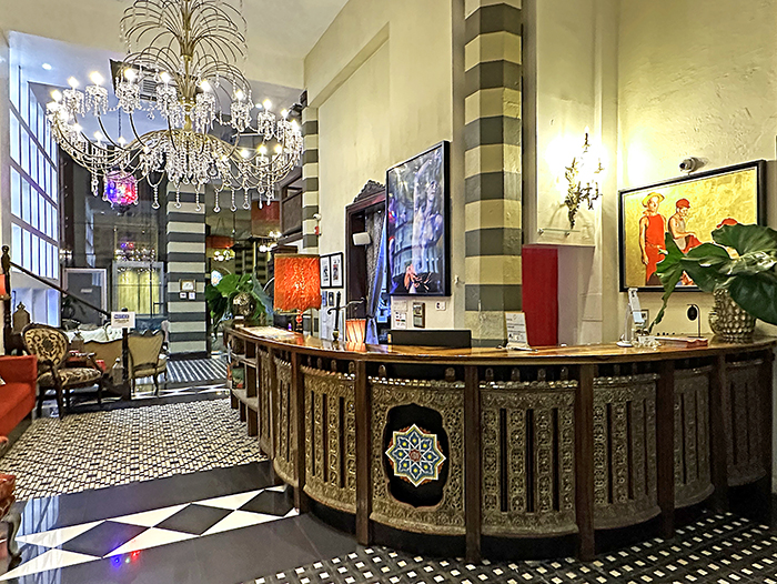 An elaborate Moroccan-style wood check-in counter in CasaBlanca Hotel lobby with chandelier and tile flooring