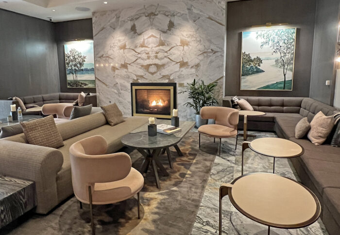 Hotel lobby with fireplace, artwork, round table, couches in beige and tan decor.