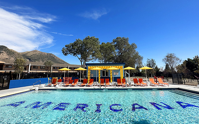 Rectangular pool with Americana lettering and colorful orange lounges and yellow umbrellas