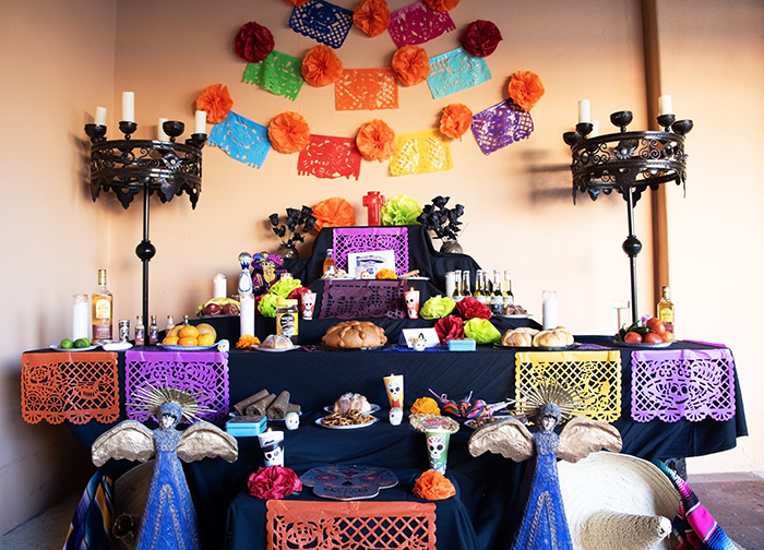 a day of the dead altar with candles, paper flags, food, drinks