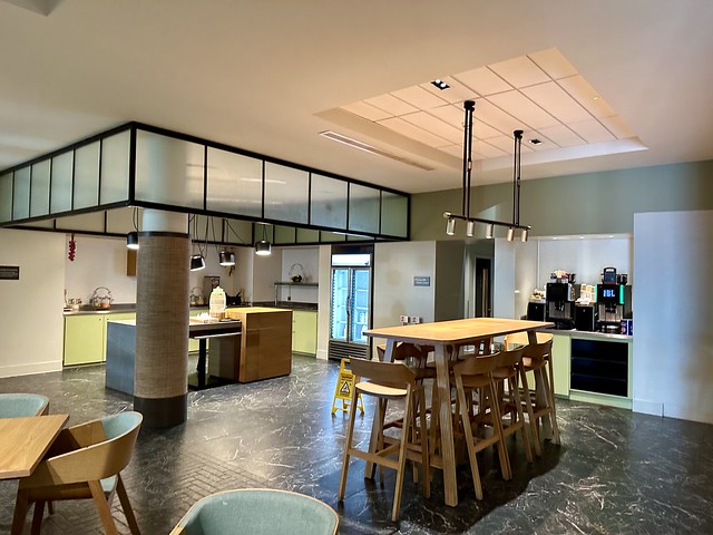 Kitchen and breakfast area at Staybridge Suites. Raised wood table seats six. Coffee and beverage station behind table. 