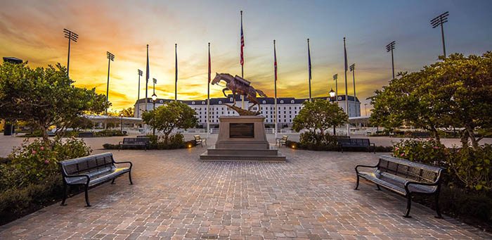 A large horse statue stands in the foreground and the white Equestrian Hotel is in the background