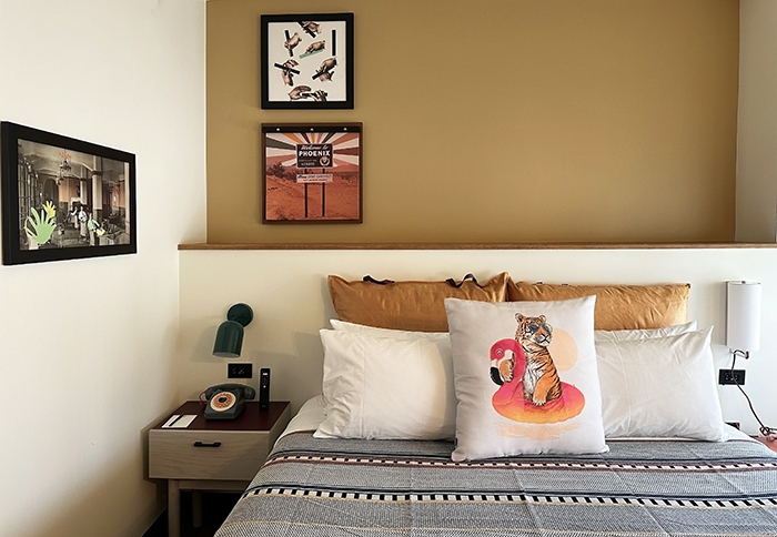 Detail of King bed with kitschy pillow and local artwork on wall